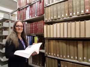 Stephanie Bartz in front of a shelf full of archivals folders