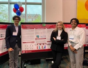Deshik, Madison, and Vaishnavi standing in front of their poster at a research symposium