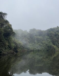 This picture showcases trees surrounding a glassy looking, reflective body of water, which actually fills a volcanic crater at the Barva Volcano