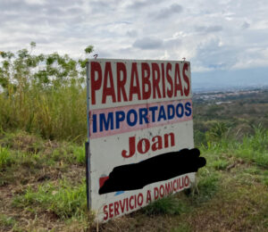 An advertisement sign in Costa Rica. It says Parabriso at the top, with Importados just below that. Below that it says Joan, with the phone number below being censored. The bottom line says servicio a domicilio.
