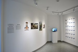 Installation view of four photographs, small tv and twenty-four sheets of letter sized paper with text. .