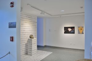 Installation view of two photographs and site-speific installation with writing on wall and floor and white bust on pedestal.