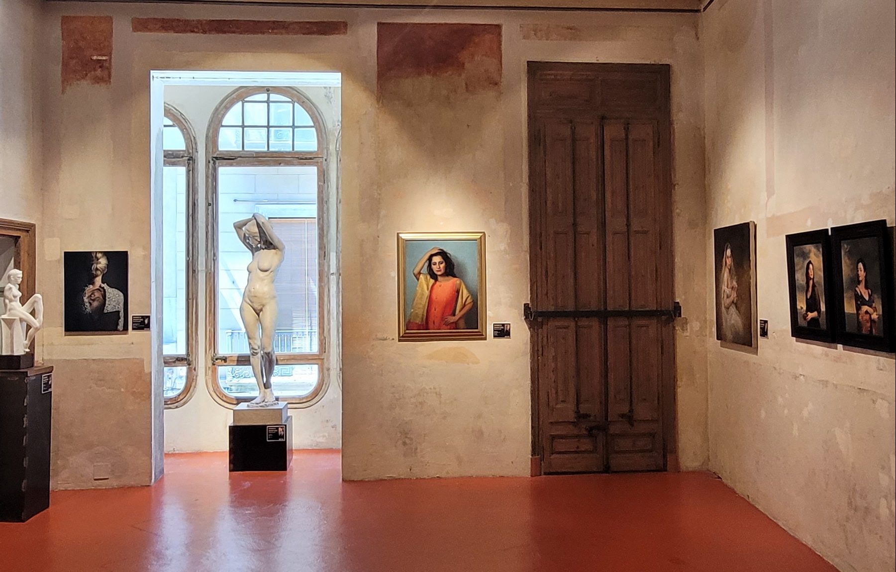 Installation view of paintings and sculptures with figures.