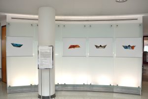 Installation view of four photographs of boats against glass.