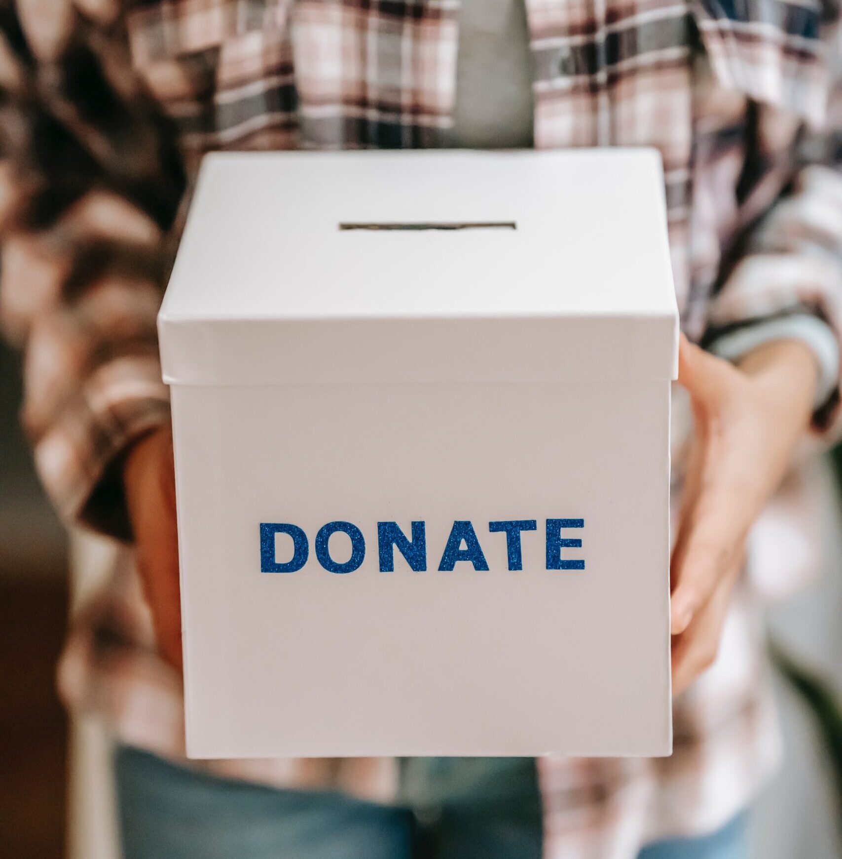 A photograph of a person holding a white box with the word, 