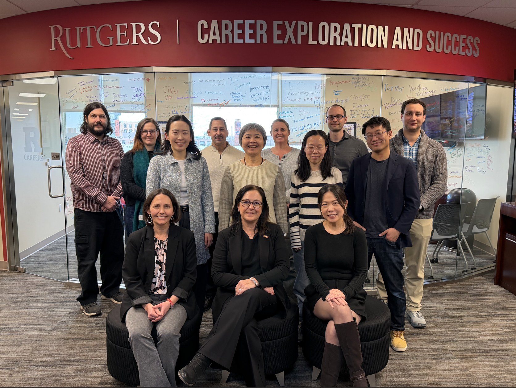 This image shows the inaugural cohort for the Faculty Career Fellows program, standing together under a sign that says "Rutgers Career Exploration Success".