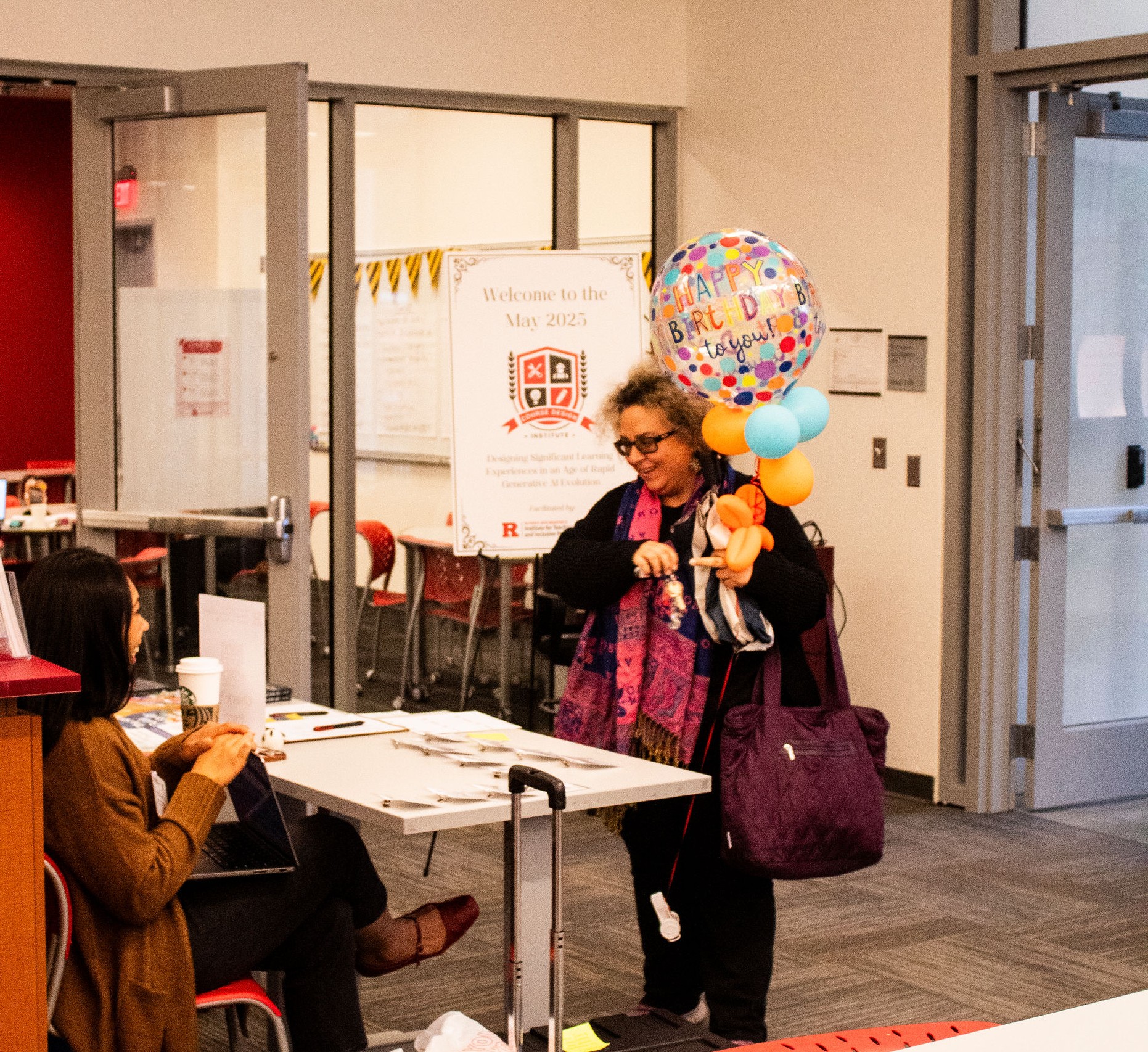A participant arrives at the sign-in desk. She is holding a balloon that says "Happy Birthday to you!"