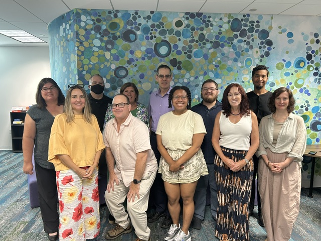 Several faculty members posing for a photo in front of a wall with polka dots