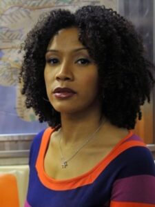 Headshot of Melissa M. Valle. A subway seat and map sit in the background.