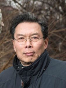 Headshot of John Kuo Wei Tchen in front of a wooded area.