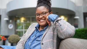 Dr. Porterfield sitting on a bench in front of 110 Warren's front entrance on the Rutgers Newark Campus.