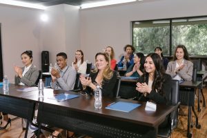 A photo of people sitting down and clapping. Everyone is wearing professional business attire.