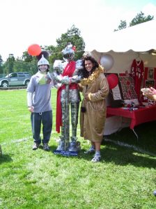 Two people dresses as the tin man and the cowardly lion posing with a knight.