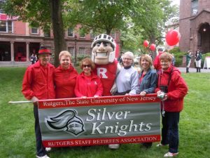 Six people posing with the Rutgers Scarlet Knight mascot in front of a banner that says, 'Silver Knights'.