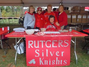 Five peple standing behind a table with a 'Rutgers Silver Knights' banner on it.