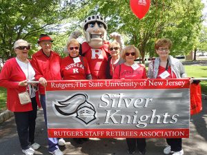 Six people posing with the Rutgers Scarlet Knight mascot in front of a banner that says, 'Silver Knights'.