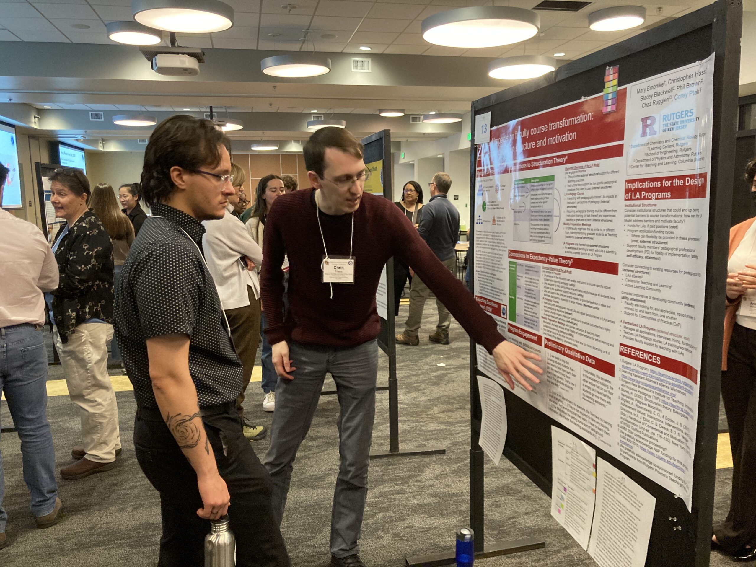 two people discussing a large-format scientific poster at a conference